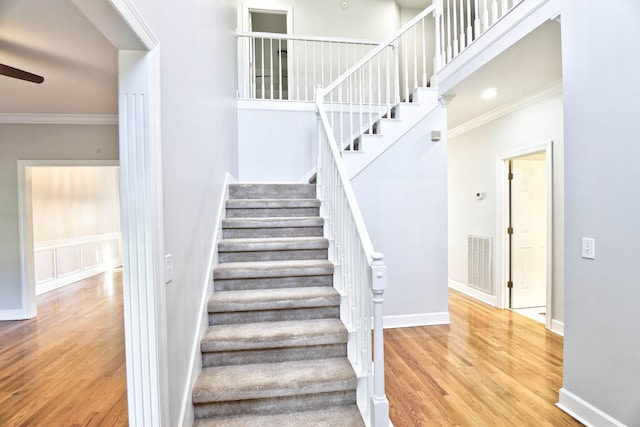 stairway with baseboards, visible vents, crown molding, and wood finished floors