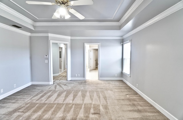 unfurnished bedroom featuring ornamental molding, carpet, a raised ceiling, and visible vents