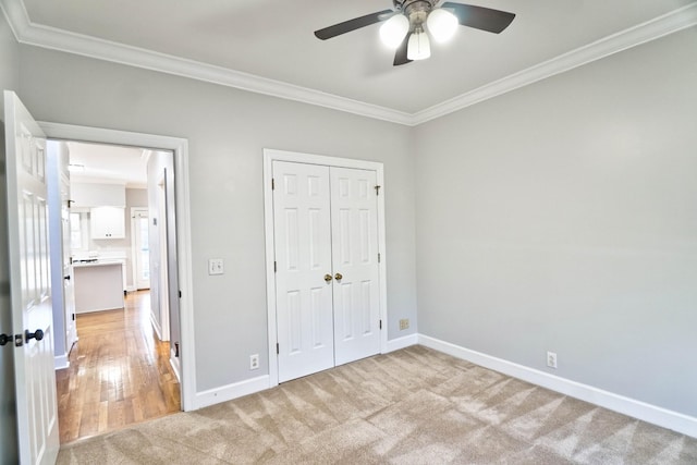 unfurnished bedroom with light carpet, baseboards, a ceiling fan, crown molding, and a closet