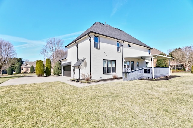 rear view of house featuring a yard, covered porch, an attached garage, ceiling fan, and driveway