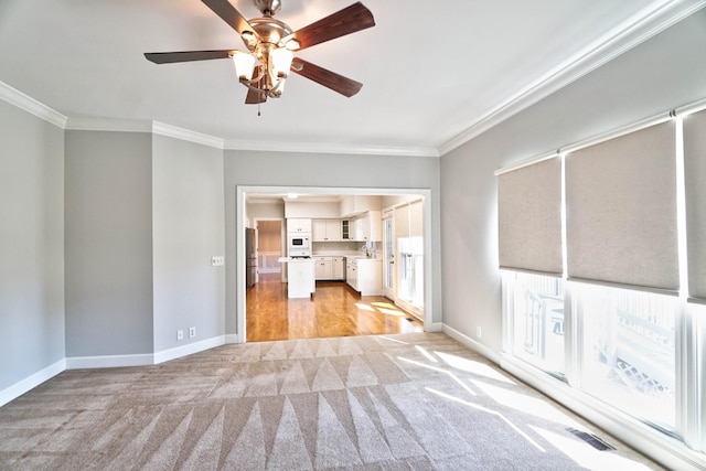 unfurnished living room with a sink, baseboards, visible vents, and crown molding