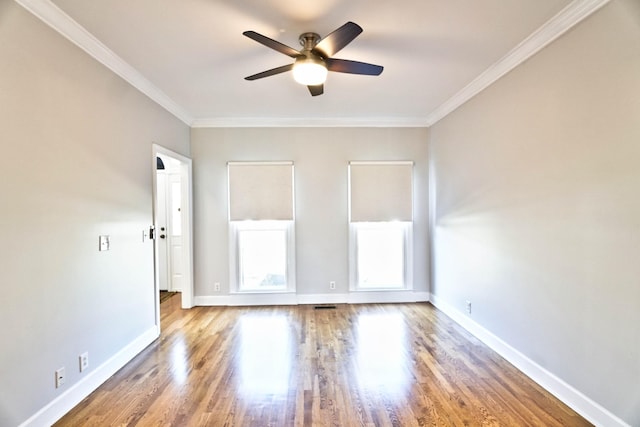 empty room with a ceiling fan, crown molding, baseboards, and wood finished floors