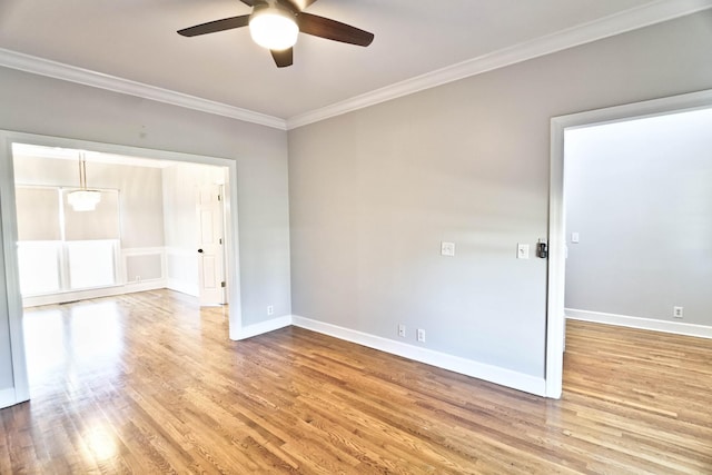 spare room featuring a ceiling fan, crown molding, baseboards, and wood finished floors