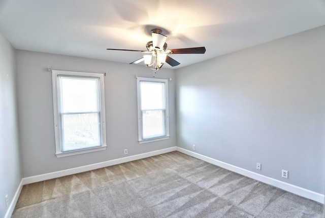 carpeted spare room featuring a ceiling fan and baseboards