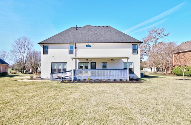 rear view of house featuring a shingled roof, ceiling fan, and a lawn