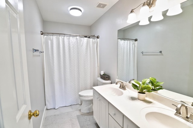 bathroom featuring visible vents, double vanity, a sink, and toilet