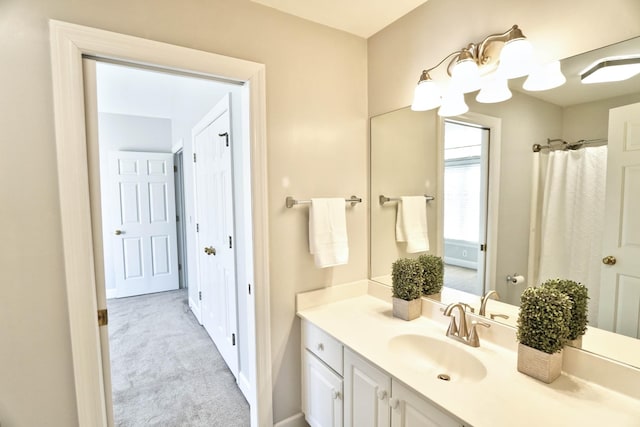 bathroom with a shower with shower curtain, vanity, and baseboards