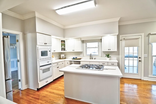 kitchen featuring light wood finished floors, appliances with stainless steel finishes, a sink, and white cabinetry