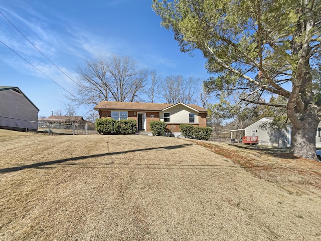 view of front of house featuring brick siding, a front lawn, and fence