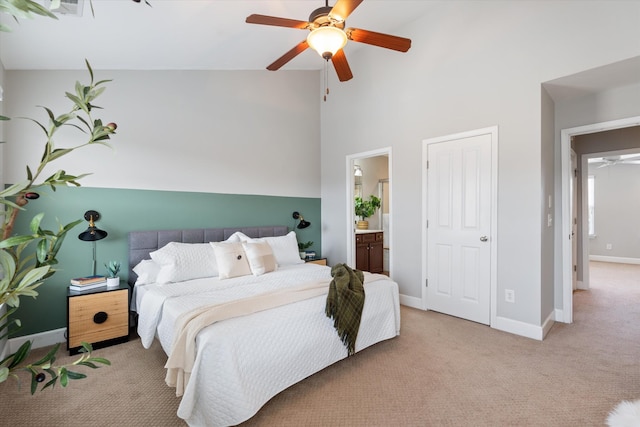 bedroom with ensuite bathroom, light carpet, ceiling fan, high vaulted ceiling, and baseboards