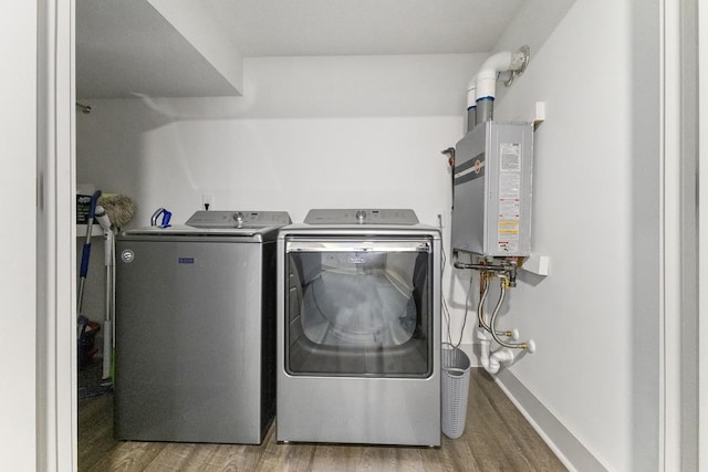 clothes washing area with light wood-type flooring, laundry area, water heater, and separate washer and dryer