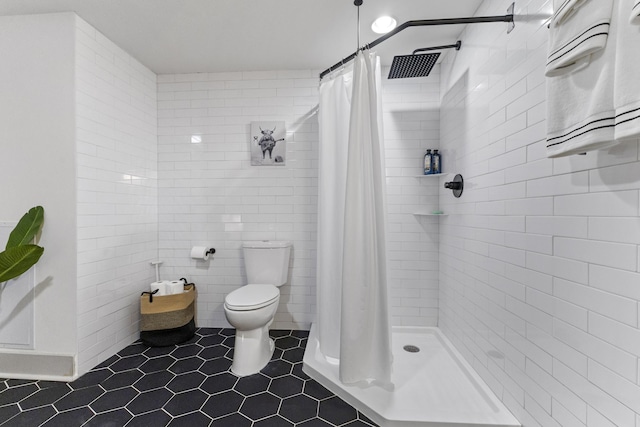 full bath with toilet, tile patterned flooring, a shower stall, and tile walls