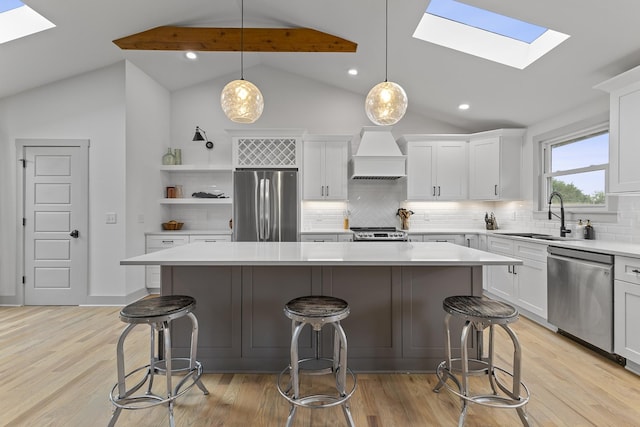 kitchen with decorative light fixtures, stainless steel appliances, light countertops, custom range hood, and a kitchen island