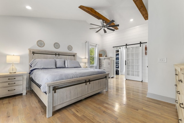 bedroom with lofted ceiling with beams, light wood-style floors, a barn door, and recessed lighting