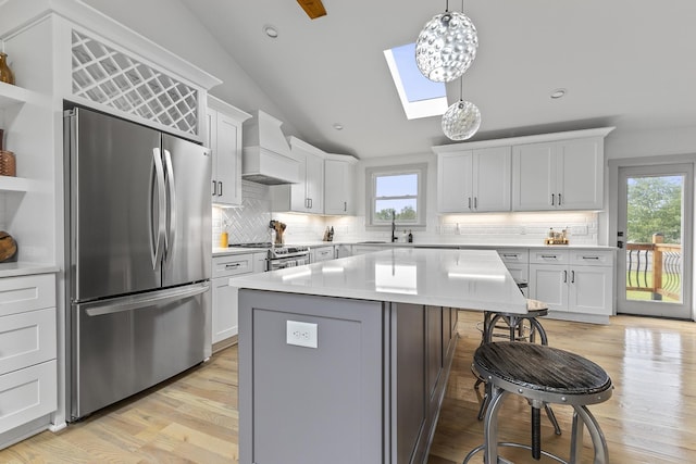 kitchen with open shelves, light countertops, custom range hood, hanging light fixtures, and appliances with stainless steel finishes