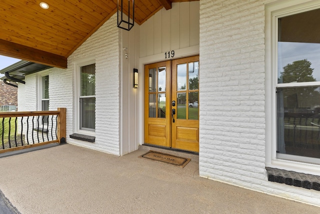 property entrance with french doors, a porch, and brick siding