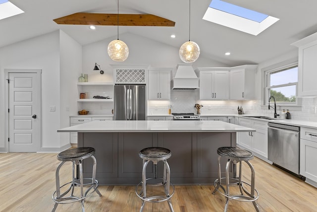 kitchen featuring custom range hood, a kitchen island, hanging light fixtures, stainless steel appliances, and light countertops