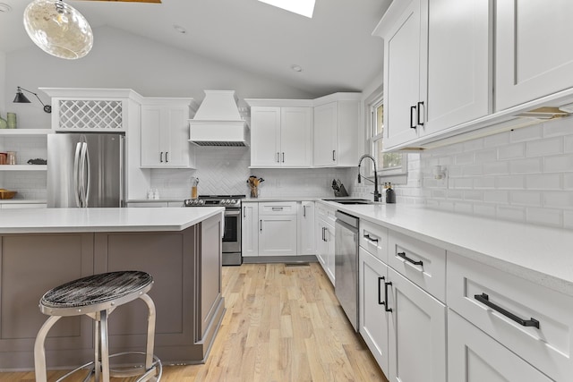 kitchen with hanging light fixtures, stainless steel appliances, light countertops, premium range hood, and white cabinetry