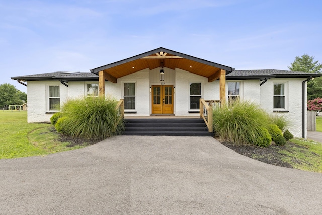 view of front of home featuring french doors, brick siding, and a shingled roof