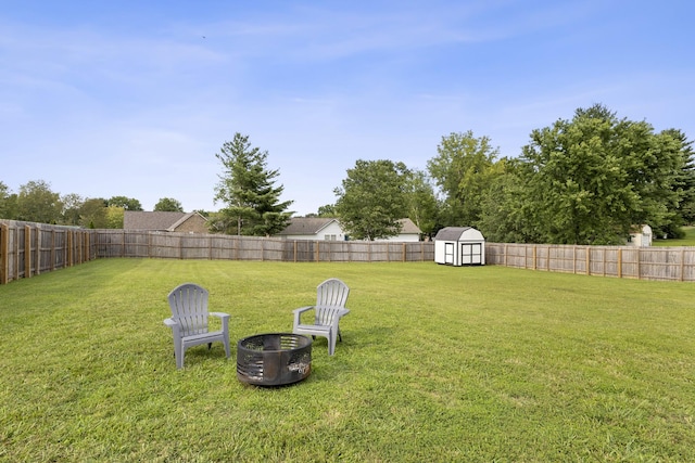 view of yard featuring a storage shed, a fenced backyard, and an outbuilding