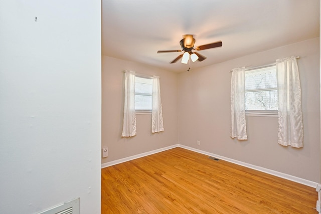 unfurnished room featuring light wood-style flooring, a ceiling fan, a wealth of natural light, and baseboards