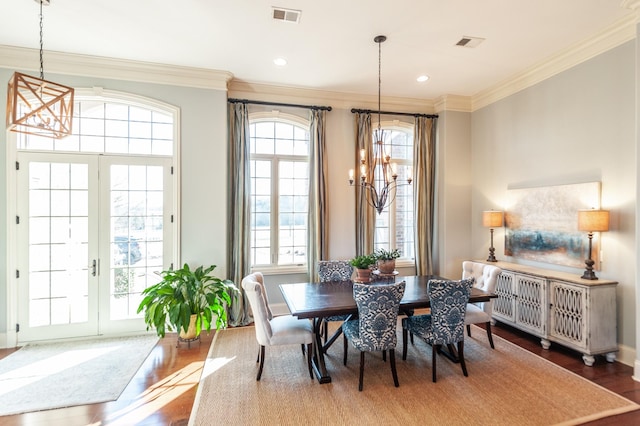 dining room featuring visible vents, ornamental molding, wood finished floors, an inviting chandelier, and french doors