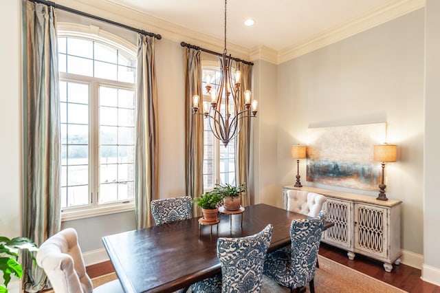 dining area with ornamental molding, a notable chandelier, plenty of natural light, and wood finished floors