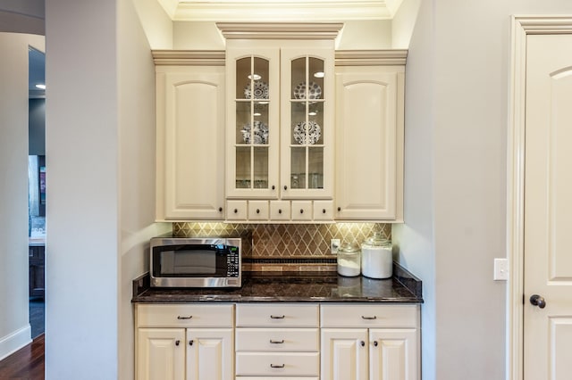 bar featuring stainless steel microwave, decorative backsplash, and crown molding