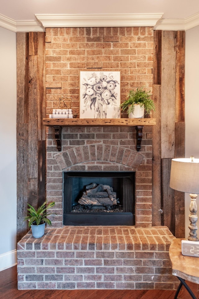 interior details with a fireplace, crown molding, baseboards, and wood finished floors