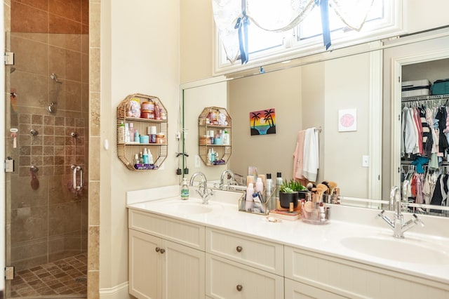 bathroom featuring a stall shower, a walk in closet, a sink, and double vanity