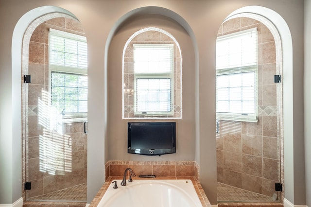 bathroom featuring a stall shower, a bath, and a healthy amount of sunlight