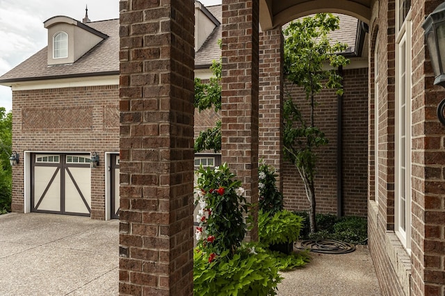 exterior space with a garage, brick siding, driveway, and a shingled roof