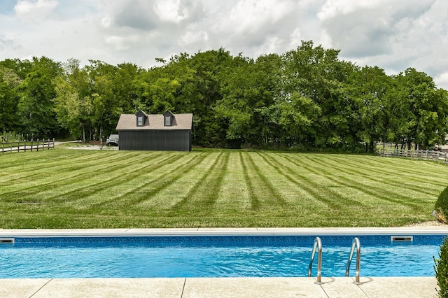 pool featuring fence, a lawn, and an outdoor structure