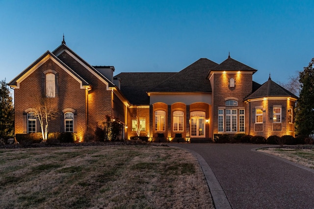 view of front of property with driveway, brick siding, and a front lawn