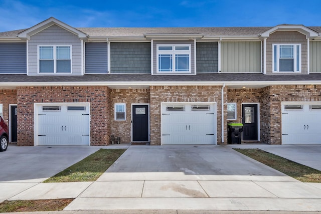 multi unit property with concrete driveway, brick siding, and roof with shingles