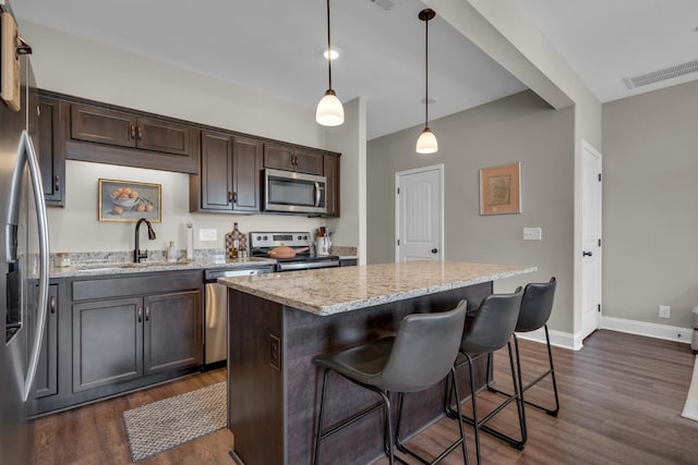 kitchen with a center island, appliances with stainless steel finishes, dark wood-type flooring, a sink, and dark brown cabinets