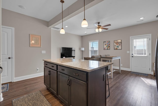 kitchen featuring dark brown cabinets, dark wood-style flooring, a breakfast bar area, and baseboards