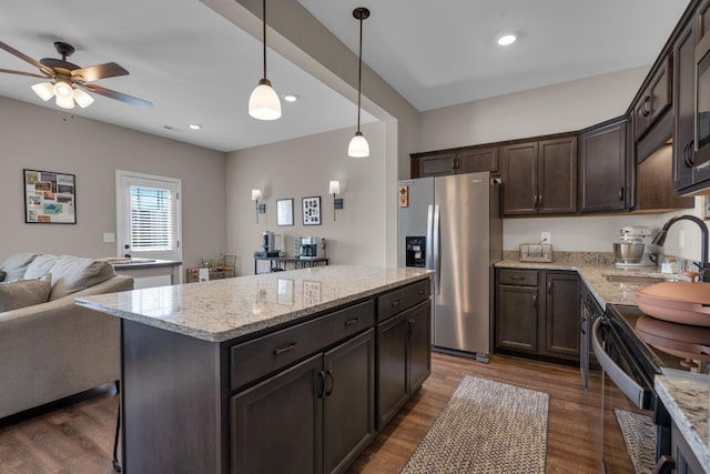 kitchen with stainless steel refrigerator with ice dispenser, dark wood-type flooring, open floor plan, dark brown cabinetry, and a sink