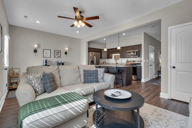 living area with a ceiling fan, baseboards, dark wood-type flooring, and recessed lighting