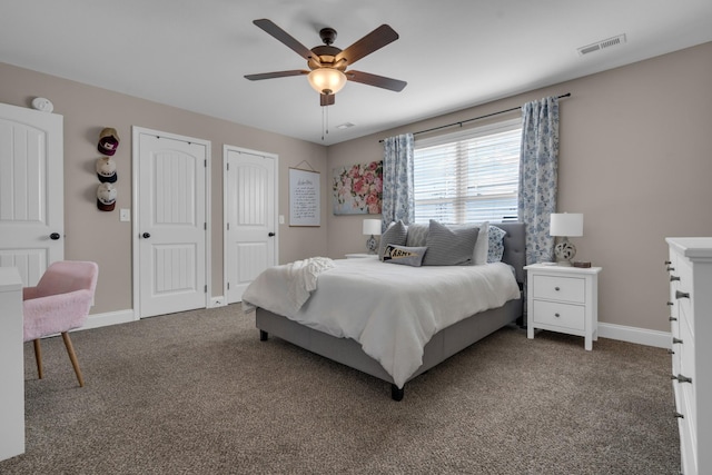 bedroom featuring two closets, visible vents, carpet flooring, ceiling fan, and baseboards