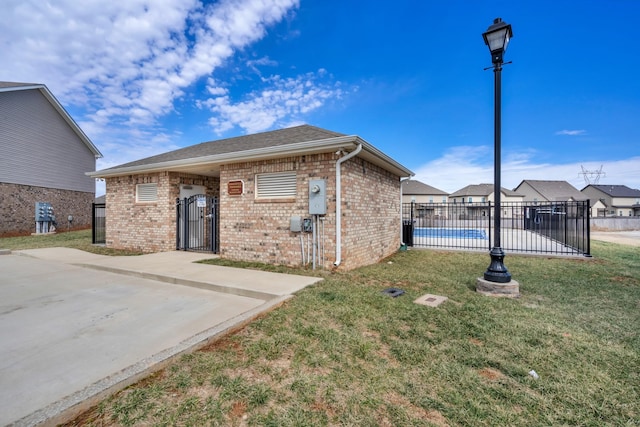 view of front of home featuring fence, a front lawn, a fenced in pool, and brick siding