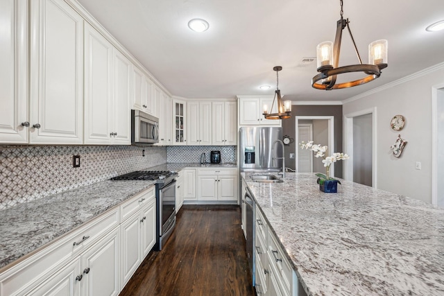 kitchen with a notable chandelier, stainless steel appliances, a sink, white cabinets, and hanging light fixtures