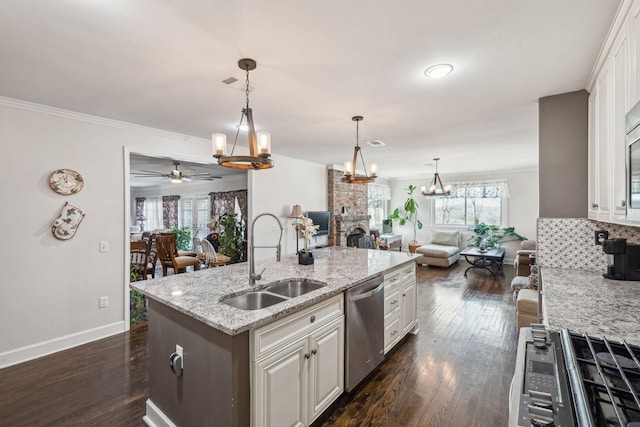 kitchen featuring appliances with stainless steel finishes, open floor plan, white cabinetry, and a sink