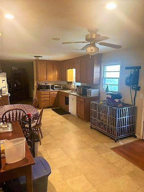 kitchen featuring dishwasher, ceiling fan, brown cabinets, freestanding refrigerator, and a sink