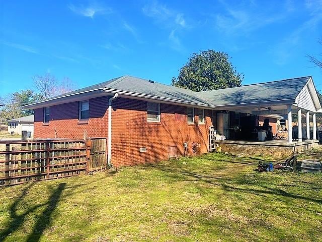 view of side of property featuring crawl space, a yard, fence, and brick siding