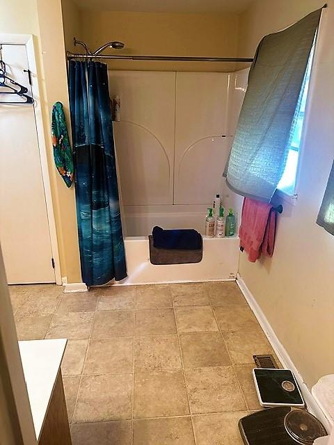 full bathroom with visible vents, shower / bathtub combination with curtain, baseboards, and tile patterned floors