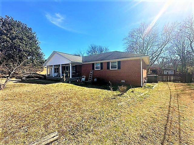 view of front of home with crawl space, brick siding, fence, and a front lawn