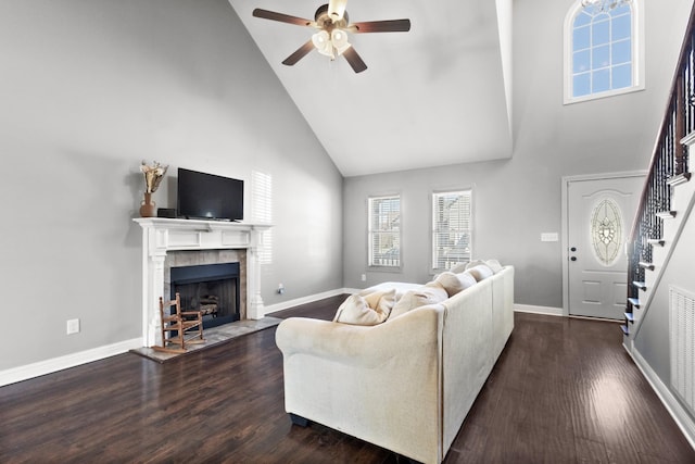 living room with dark wood-type flooring, stairway, a tiled fireplace, and baseboards