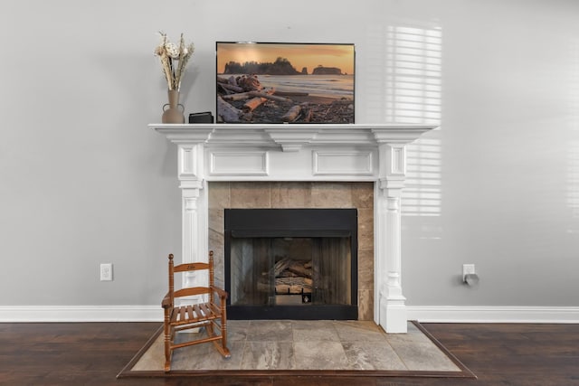 details with baseboards, a tiled fireplace, and wood finished floors