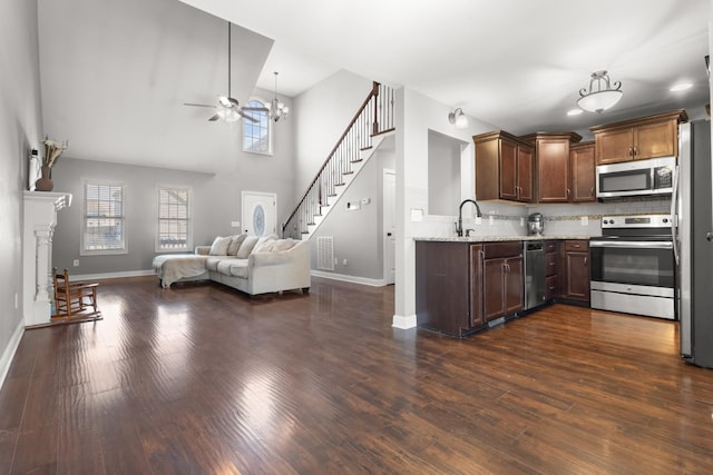 kitchen featuring stainless steel appliances, baseboards, open floor plan, backsplash, and dark wood-style floors